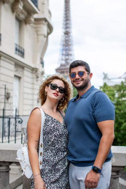 A blond woman and Mediterranean-looking man posing at the Avenue de Camoens lookout with view of Eiffel Tower