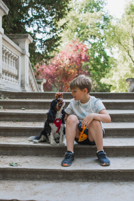 Boy feeds dog on the stairs at parc Monceau