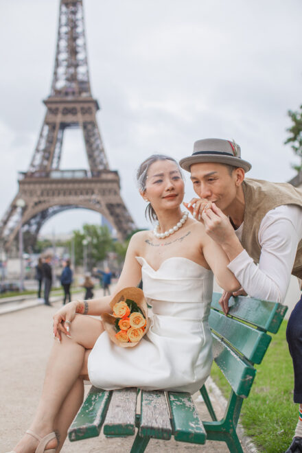 Newlyweds sitting on a park bench in Trocadero in front of the Eiffel Tower. The groom is kissing his bride's hand Radina Dianova - Paris based photographer