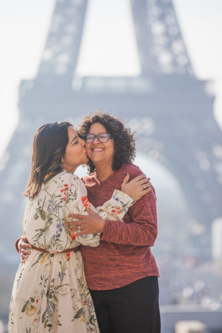 A woman kissing her wife in front of the Eiffel Tower during an LGBTQ friendly photoshoot in Paris