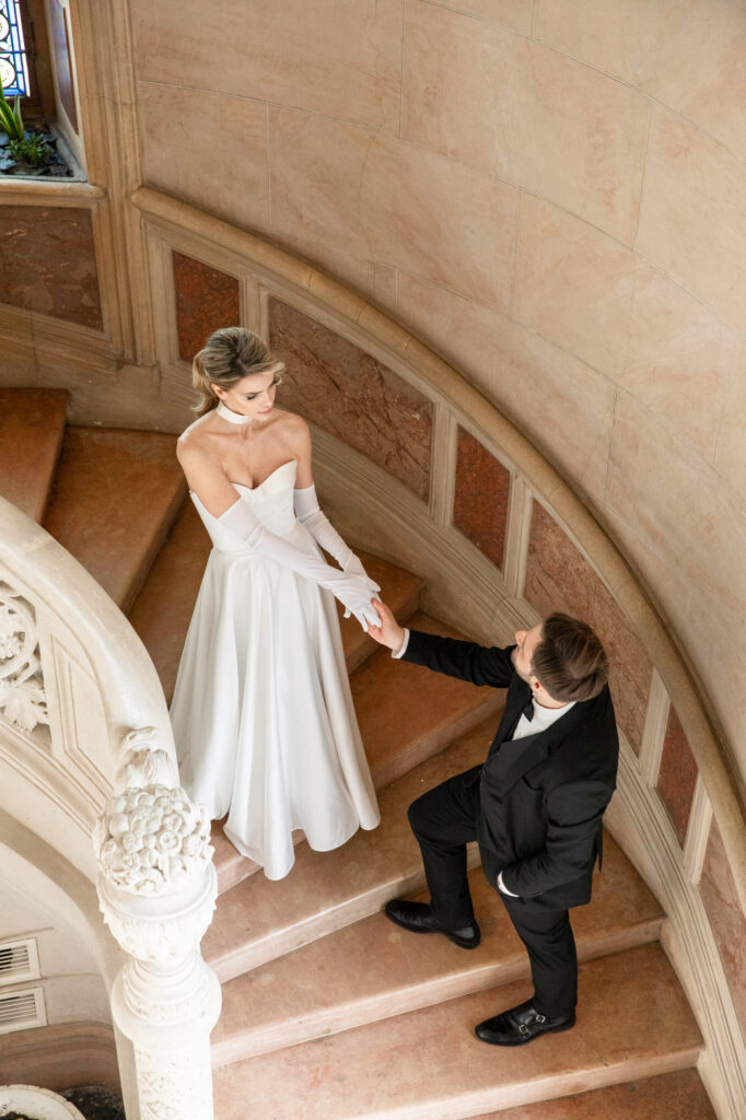 Bride and groom on curved stone staircase inside Chateau Sainte Sabine in Burgundy