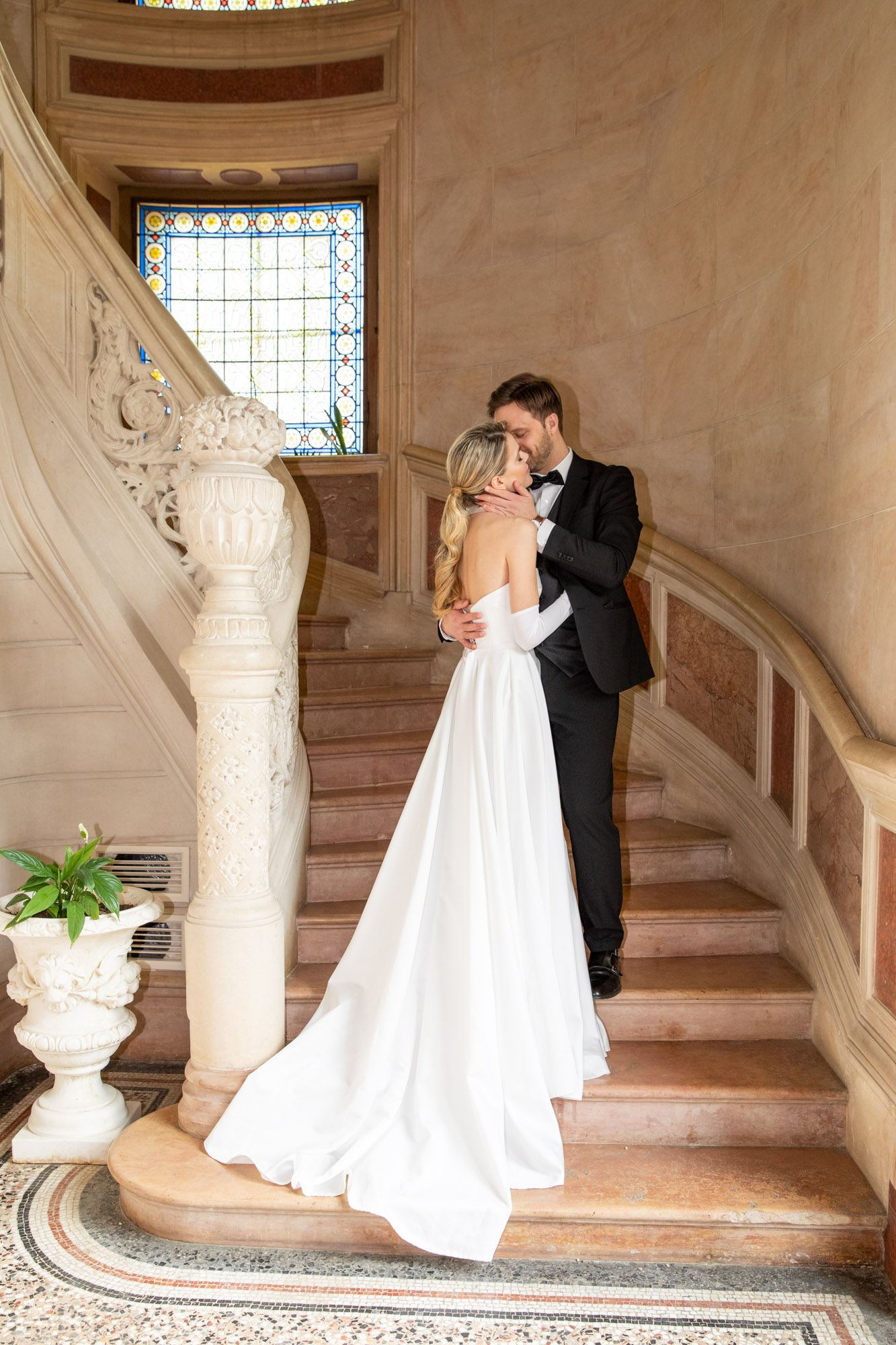 Bride and groom kissing on elegant château staircase during Burgundy wedding portrait session